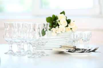 Clean plates, glasses and cutlery on white table