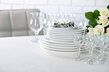 Clean plates, glasses and cutlery on white table