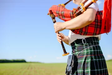 Männchen, das schottische traditionelle Pfeifen auf grünem Sommer draußen spielt © gorosi