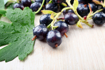 Pile of wet black currants on wooden table, closeup
