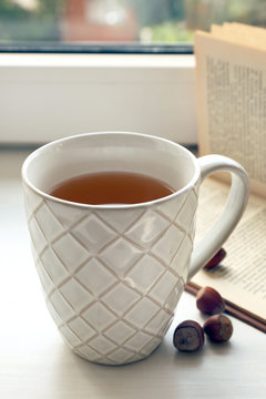 Cup of tea with open book on windowsill, closeup