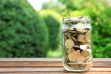 Coins in money jar on table outdoors