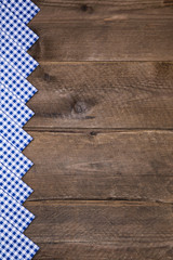 Rustikaler bayerischer Holz Hintergrund in braun mit blau weiß kariertem Band als Werbefläche.