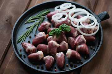 Raw fresh chicken hearts in a cast-iron frying pan, close-up