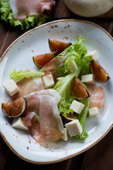 Salad with fig fruits, cheese and ham, selective focus