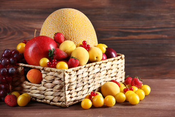 Fototapeta na wymiar Assorted of fresh fruits in wicker basket on wooden background