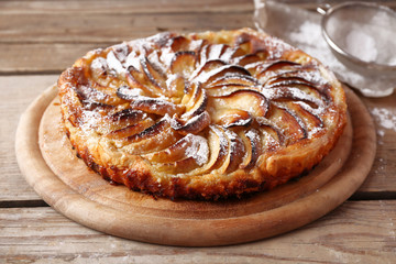 Homemade apple pie on cutting board on wooden background