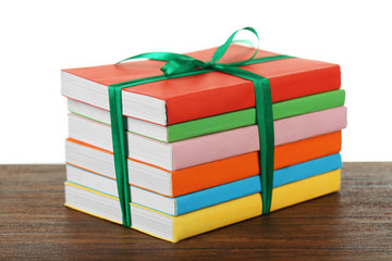 Stack of books with ribbon on light background