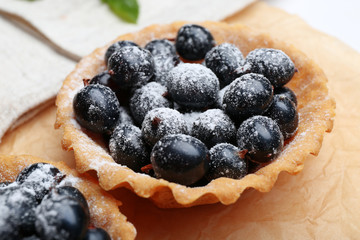 Delicious crispy tart with black currants on parchment, closeup