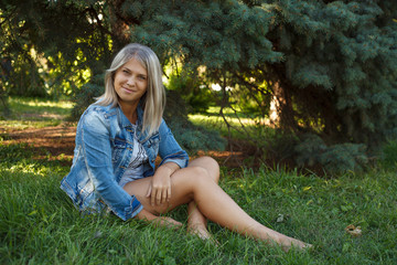 Obraz premium Posing beautiful girl sitting on the lawn in the park; outdoors.