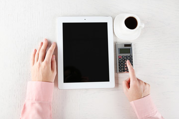 Hands working in the office with tablet and calculator on white table