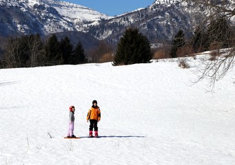 Two children with helmet and snowshoes into the mountains