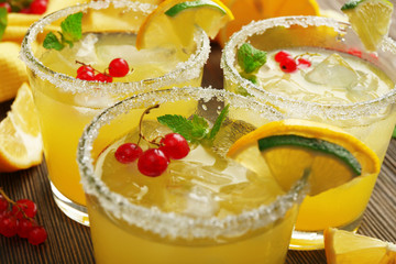 Glasses of lemon juice with red currants on wooden table, closeup