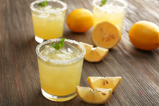 Glasses of lemon juice on wooden table, closeup