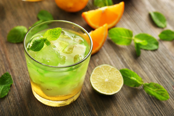 Glass of lime juice with orange on wooden background