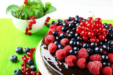 Delicious chocolate cake with summer berries on green tablecloth, closeup