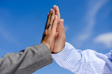 Two hands clap together under blue sky. Business man and woman