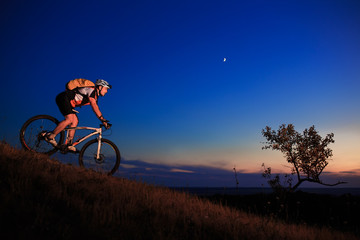 Fototapeta na wymiar Silhouette of a biker and bicycle on sunset background.