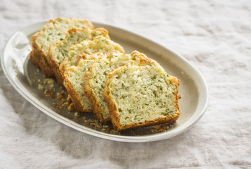 cake with cheese and herbs on an oval plate on a light surface