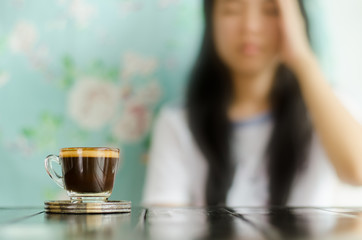 The woman,when not drink the cup of coffee, have a headache