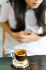The woman drink coffee and make a stomachache.