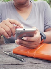 Woman using smart phone with book and pen