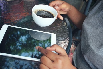 Woman drinking hot coffee with tablet