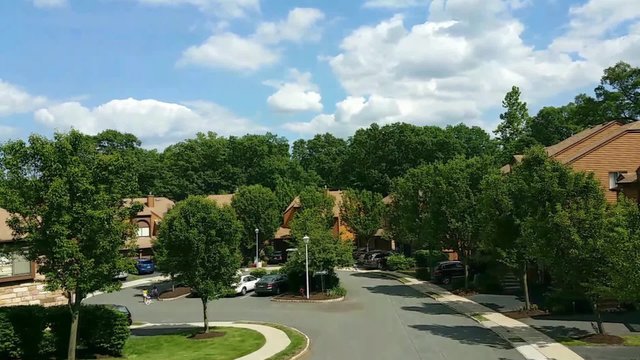Panning timelapse in an american suburban residential neighborhood in Rockaway, New Jersey. Moving clouds cast their shadows on a sunny summer day.