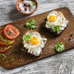 toast with feta cheese and fried quail egg, fresh tomatoes on a light wooden surface - a healthy Breakfast or snack