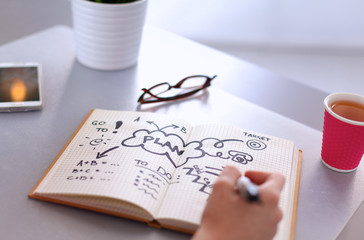 Young woman writes to diary on a white table
