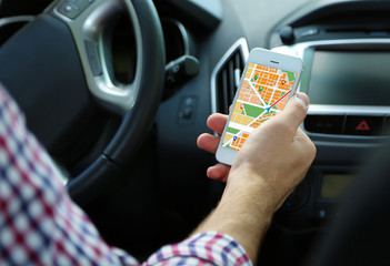Man sitting in the car and holding smart phone with map gps navigation application