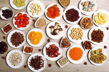Different products on saucers on wooden table, top view