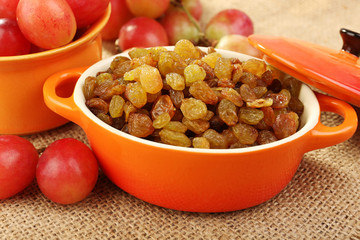Raisins in bowl with grapes on table close up