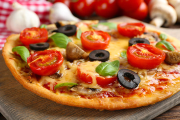 Tasty pizza with vegetables and basil on table close up