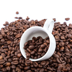 Coffee beans and ceramic cup on white background.