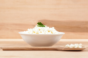 Fresh cottage cheese in a white bowl with spoon spoon.