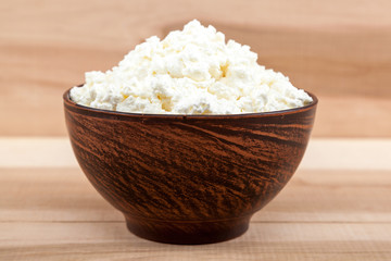 Fresh cottage cheese in  bowl on a wooden table