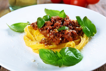 Pasta Bolognese with parmesan and basil on plate close up