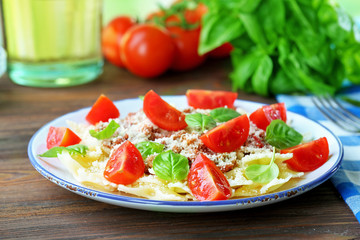 Pasta bolognese with cherry tomatoes in white plate on wooden table, closeup