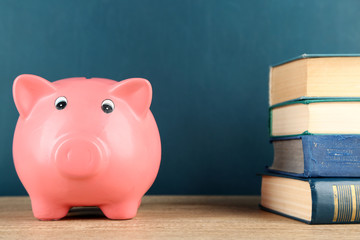 Piggy bank with books on blackboard background
