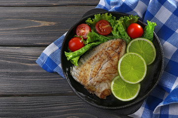 Dish of fish fillet with salad and lime on table close up