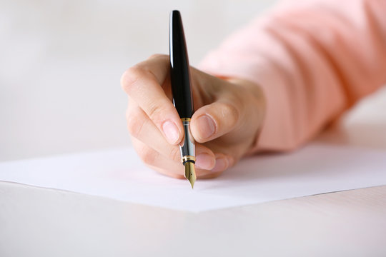 Female hand with pen writing on paper at workplace