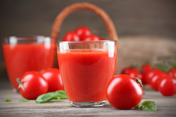 Glasses of tomato juice with vegetables on wooden table close up