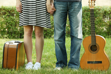Young couple with vintage suitcase and guitar outdoors