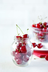 Cherries in glass bowl on table, on light background