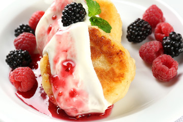Fritters of cottage cheese with berries in plate, closeup