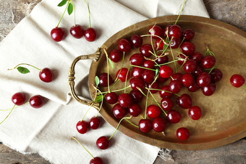 Cherries on tray, on wooden background