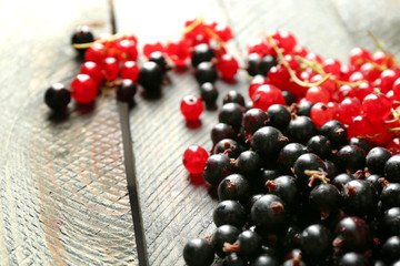 Ripe red and black currant on wooden background