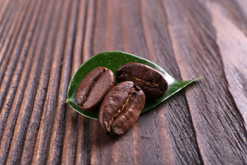 Coffee beans with leaf on wooden background