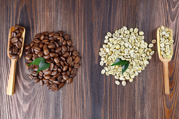 Green and brown coffee beans with spoons on wooden table close up